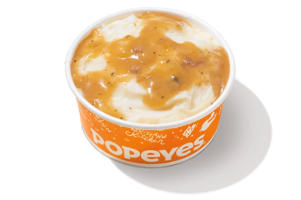 Popeyes mashed potatoes with Cajun gravy in an orange container."