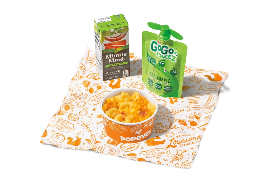 "Mac & Cheese Kids Meal with a cup of mac and cheese, a Minute Maid juice box, and a GoGo SqueeZ applesauce pouch, on a branded napkin."