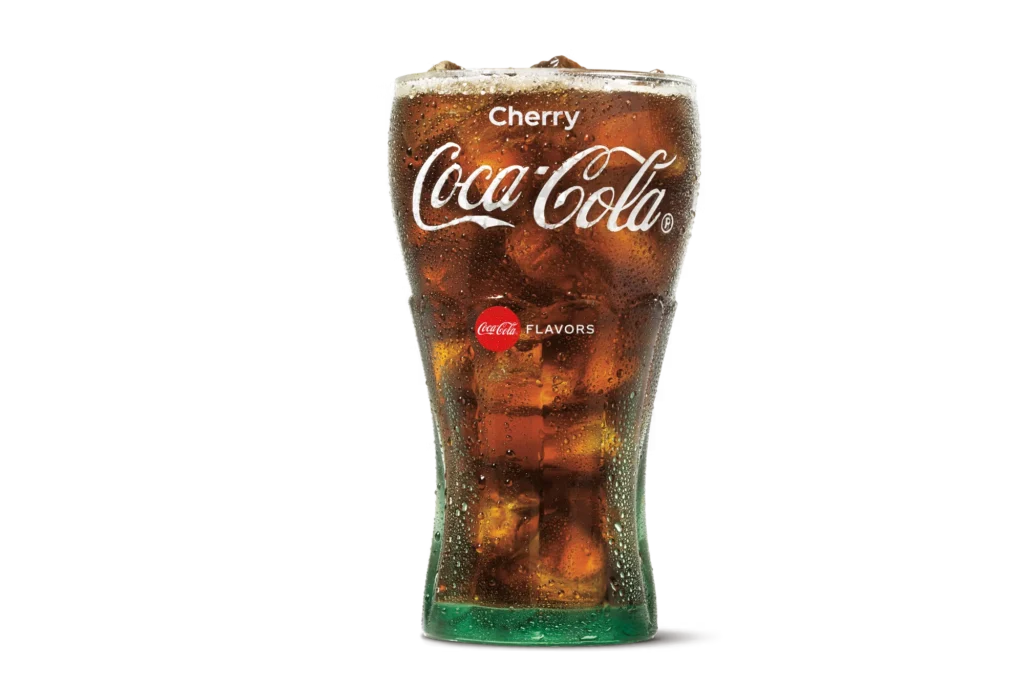 "Glass of Cherry Coke with ice cubes, Cherry Coca-Cola logo on the glass, on a white background."