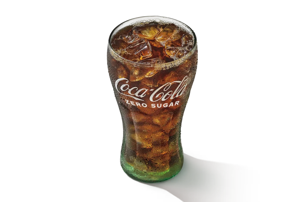 "Glass of Coca-Cola with ice cubes, branded logo visible, on a white background."